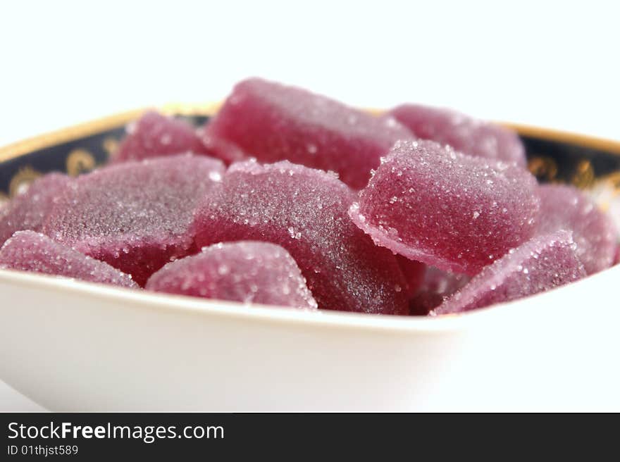 Fruit candy in a square plate with patterns on a white background