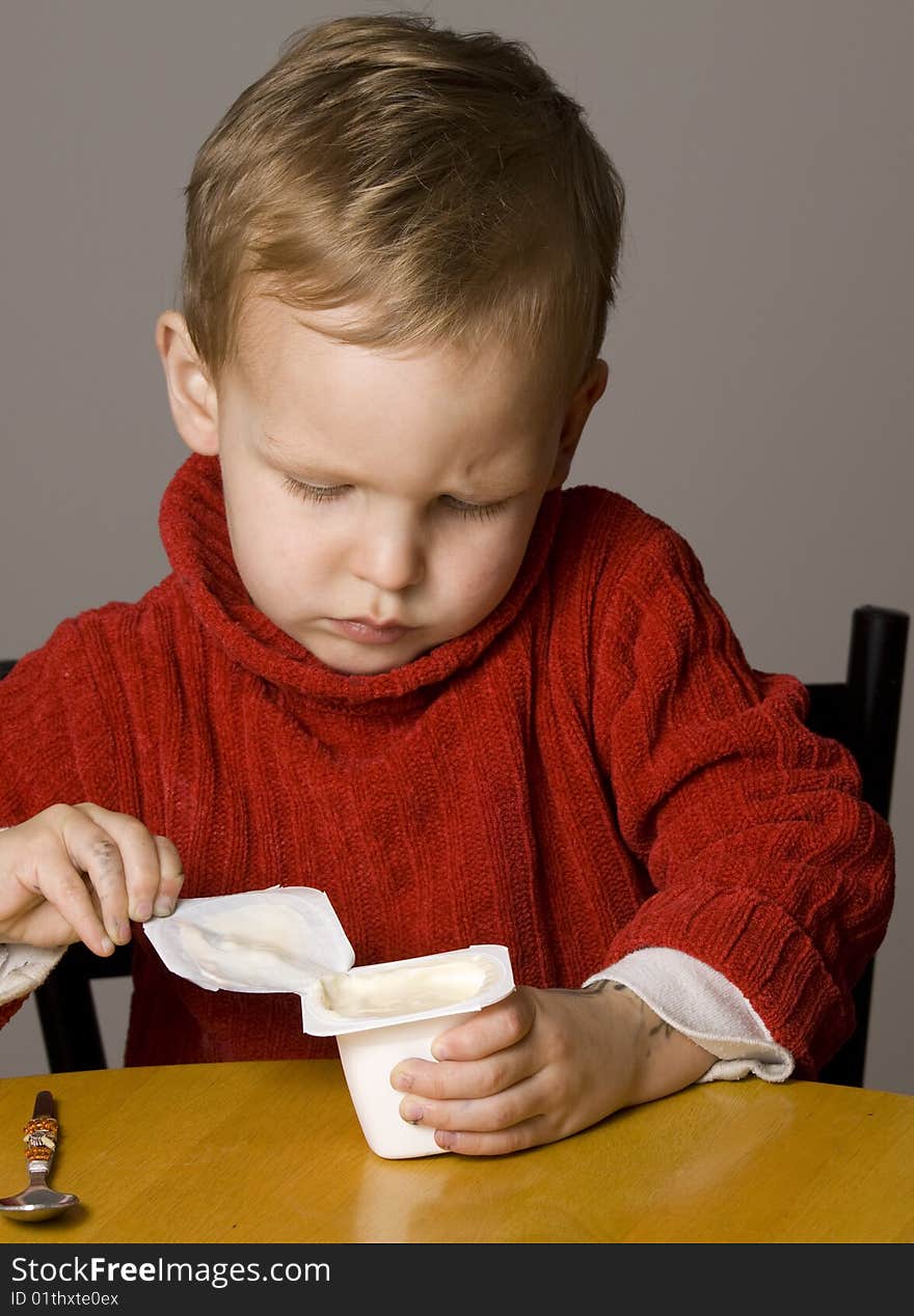 Little Boy opening a yogurt or yoghurt. Little Boy opening a yogurt or yoghurt