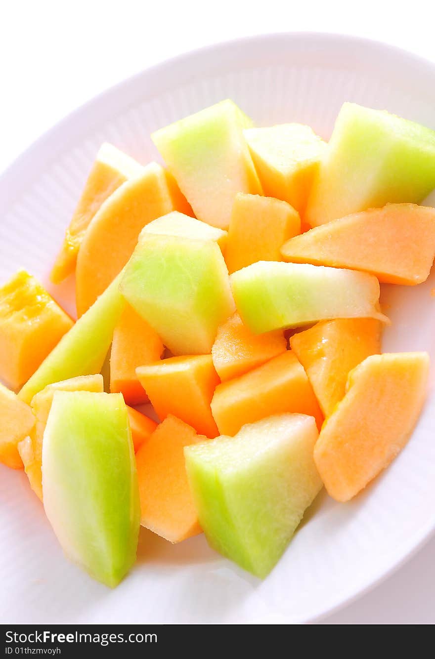 Juicy sliced melon on plate, isolated on white background.