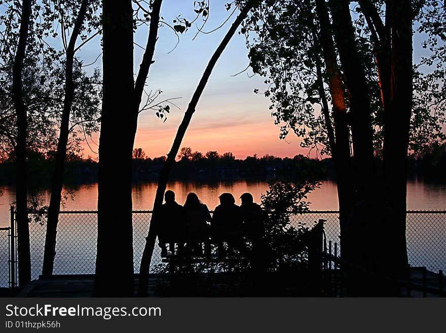 Group of firends sitting watching the sunset at the lake. Group of firends sitting watching the sunset at the lake