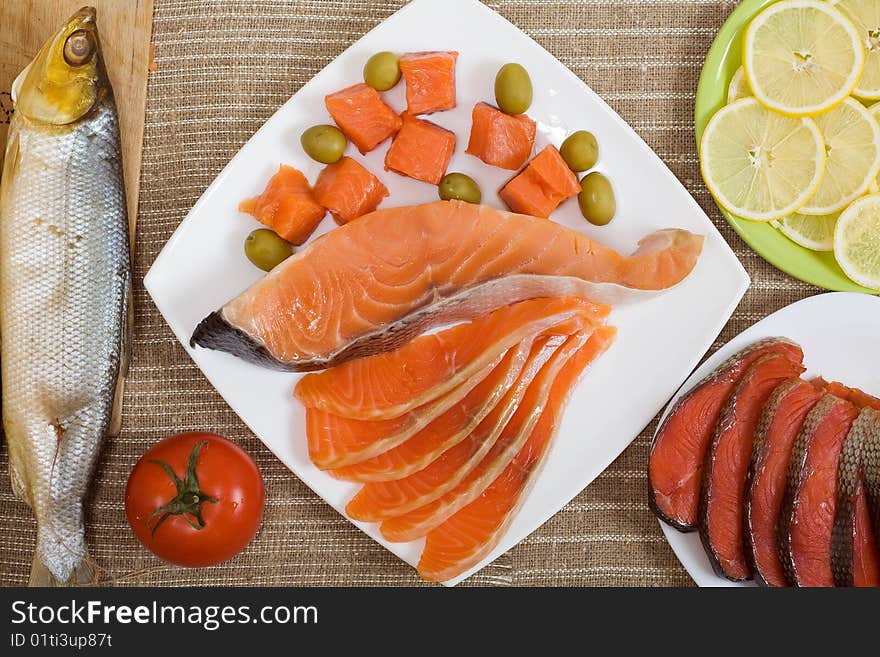 Different kinds of fish with sliced lemon, olives and tomato. Different kinds of fish with sliced lemon, olives and tomato