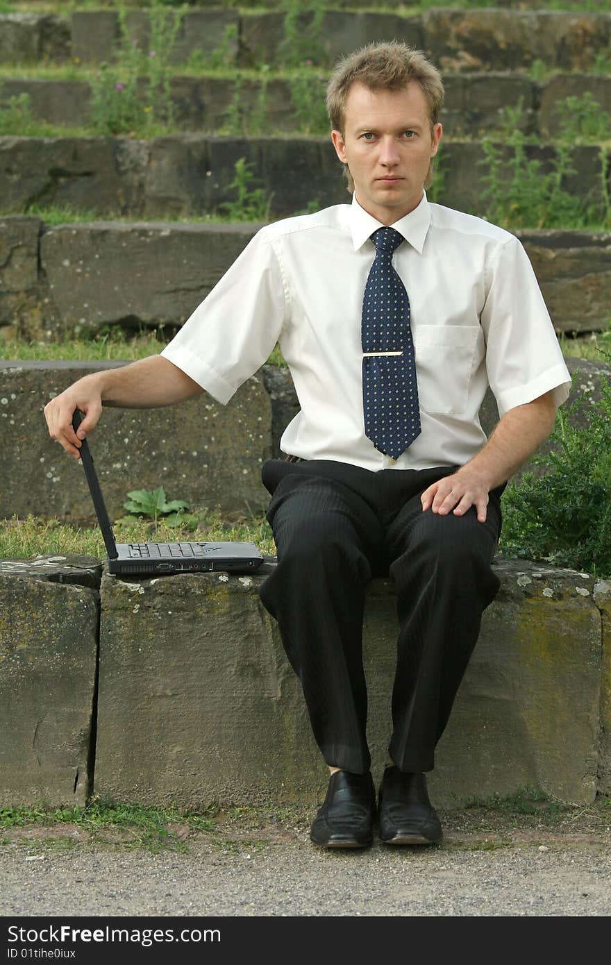 Serious businessman with laptop computer sitting on the steps. Serious businessman with laptop computer sitting on the steps