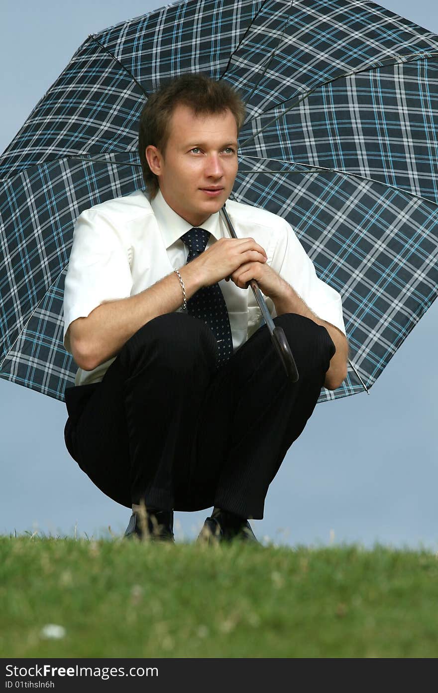 Man with umbrella sitting on the grass