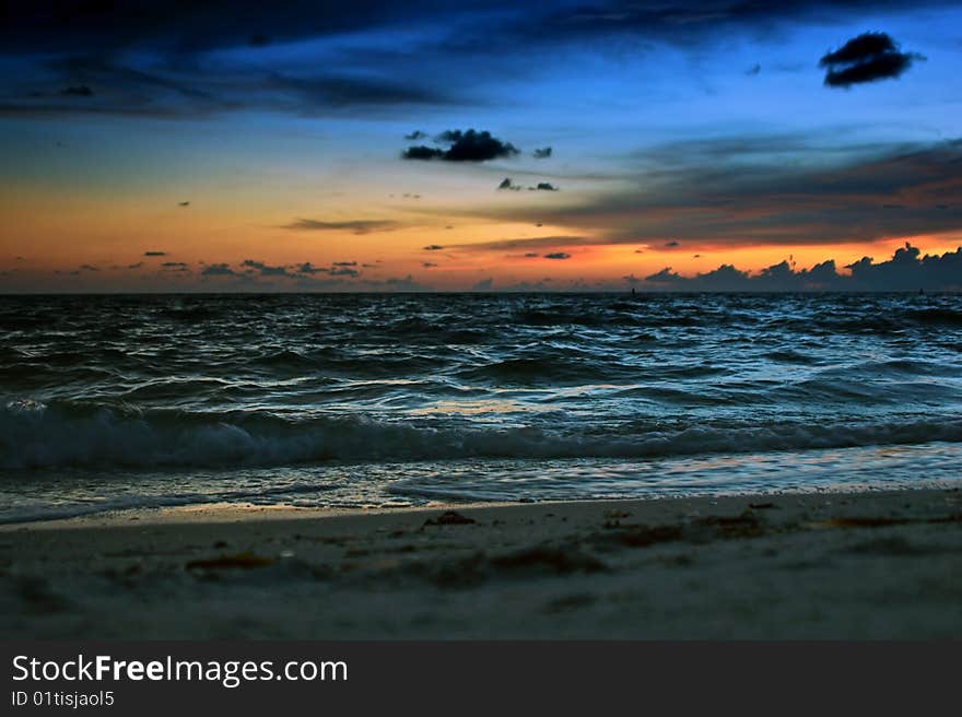 A colorful sunset creates the backdrop for the waves rolling into the shore at the beach. A colorful sunset creates the backdrop for the waves rolling into the shore at the beach.