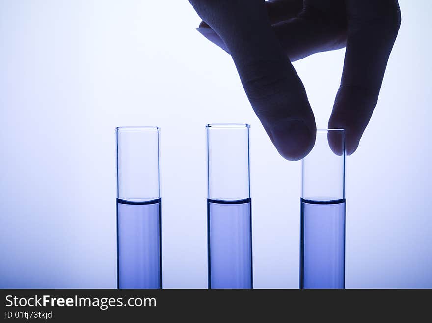 Hand pulling test tube out of test tube rack. Hand pulling test tube out of test tube rack