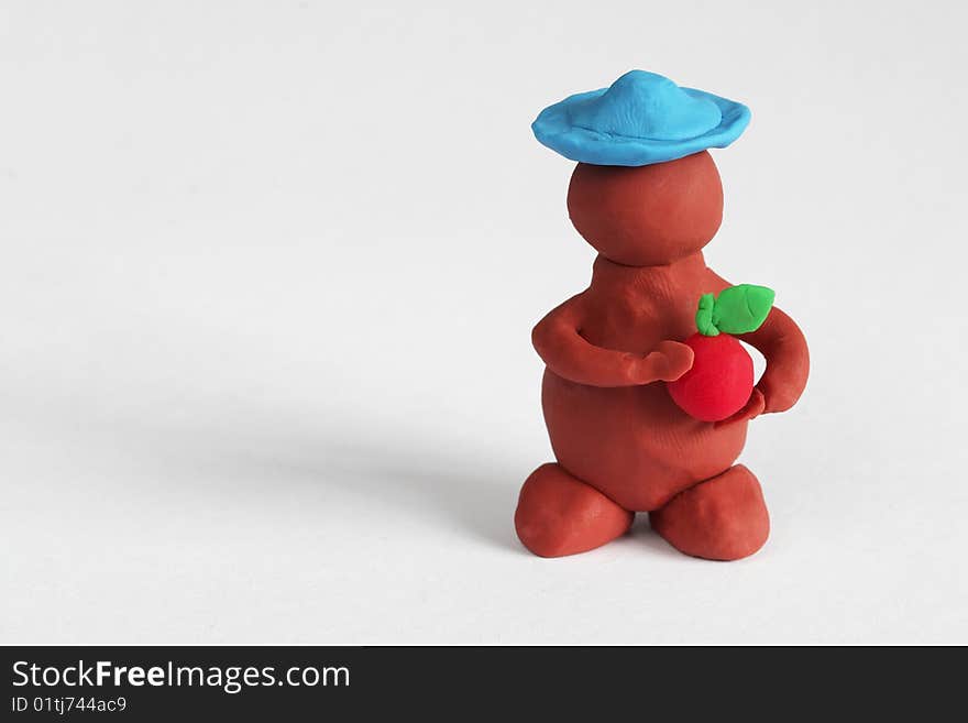 Plasticine man keeping a red apple over grey background