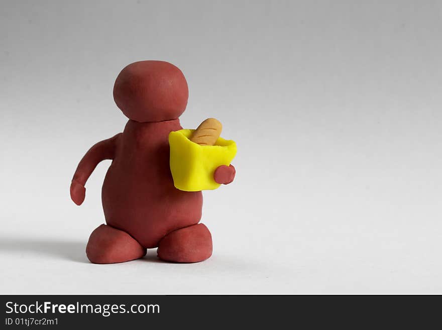 Plasticine customer keeping a bag with a bread over grey background. Plasticine customer keeping a bag with a bread over grey background