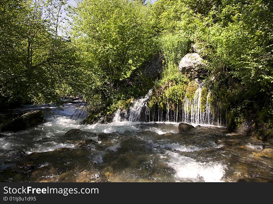 Mountain River in the summer with blue sky and trees in the background. Mountain River in the summer with blue sky and trees in the background