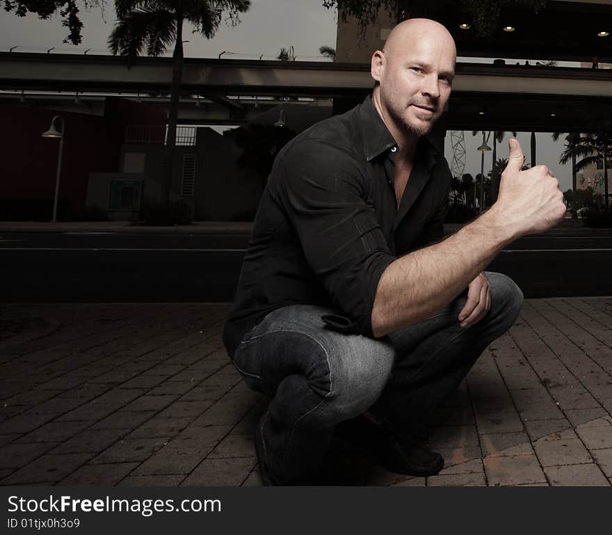 Man smiling squatting and showing a thumbs-up gesture. Man smiling squatting and showing a thumbs-up gesture