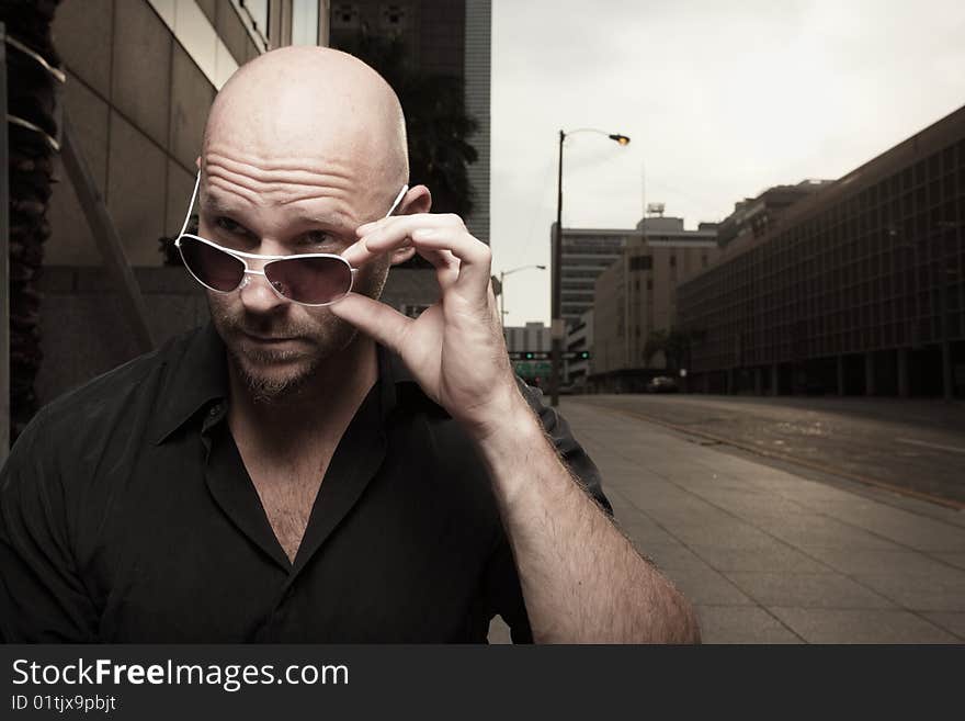 Bald man removing his shades and looking away