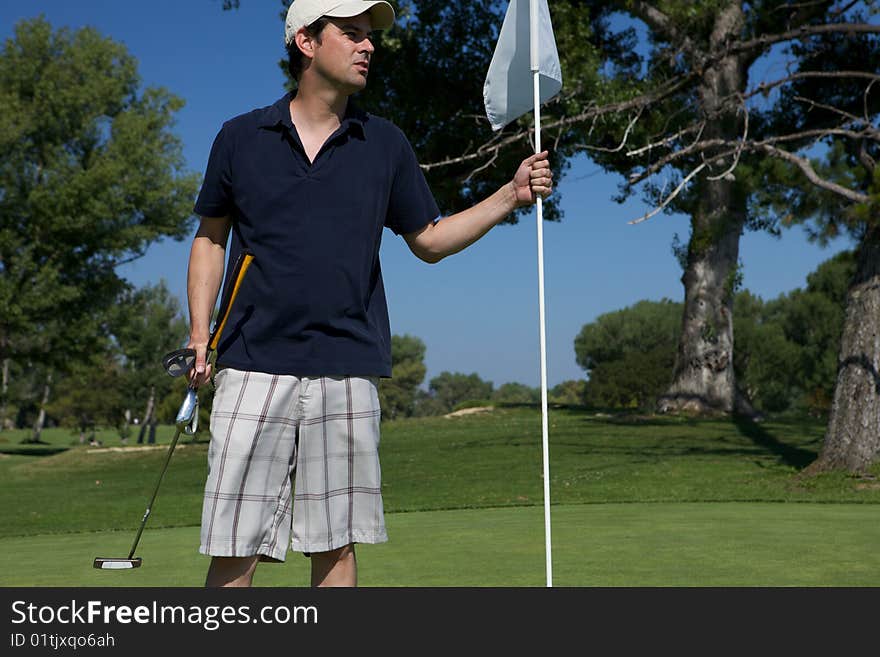 A Man golfing swinging his club toward the tee