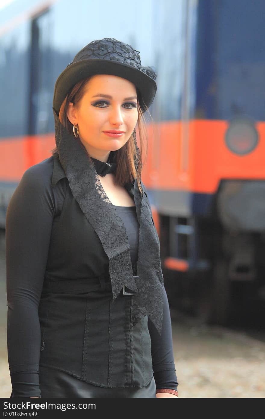 Gothic girl with black hat, brown eye's and red lipstick smiling in the camera.