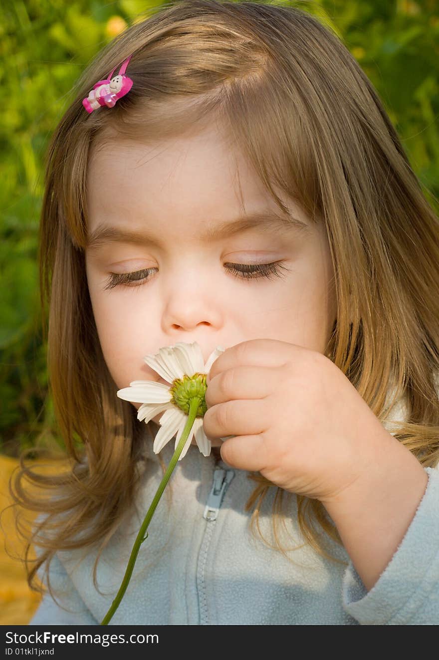 Little girl smelling camomile