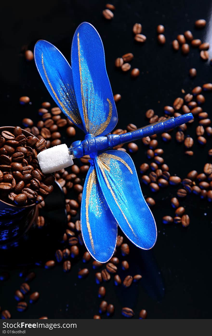 Balance - blue dragonfly at beans of coffee with sugar