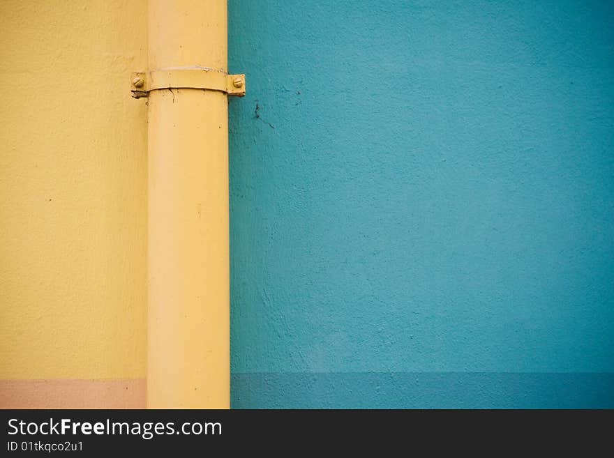 Rain gutter in front of a colorful wall.