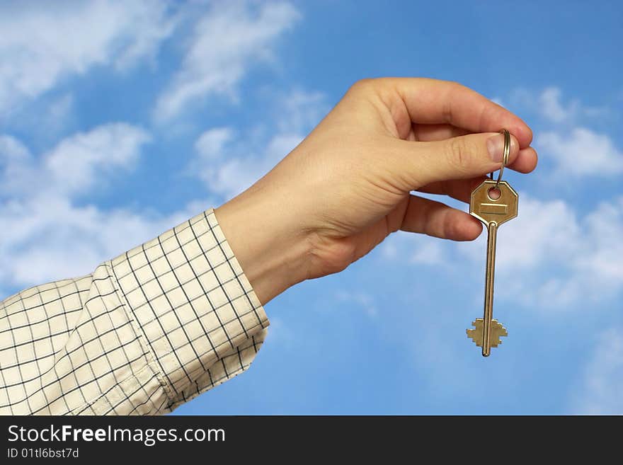 Hand holding a key over sky and clouds backgound