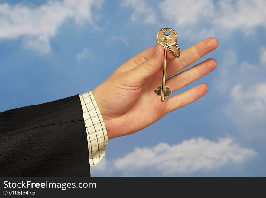 Hand holding a key over sky and clouds backgound