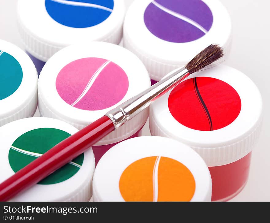 Group of colorful paint cans with brush to background