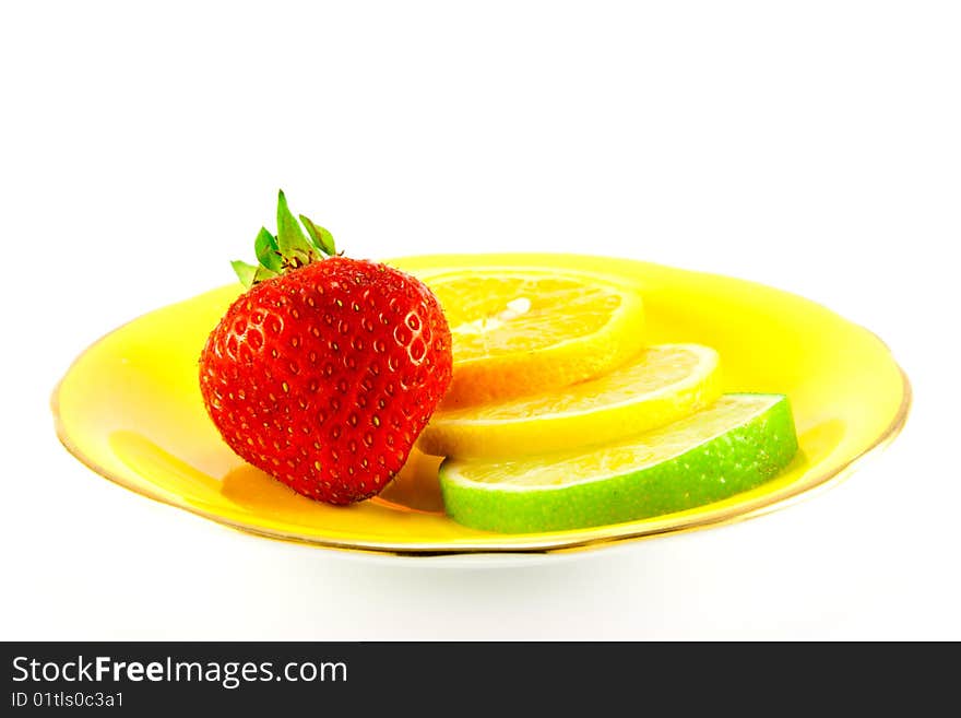 Slice of lemon, lime and orange with a red juicy strawberry on a fancy yellow plate with a white background. Slice of lemon, lime and orange with a red juicy strawberry on a fancy yellow plate with a white background