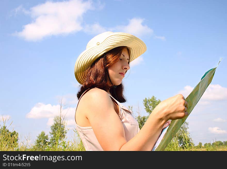 The girl on the summer meadow, considering a map. The girl on the summer meadow, considering a map