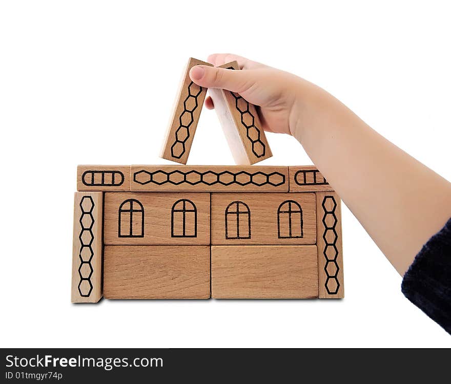 Children's hand building house from wooden toy blocks isolated on white. Children's hand building house from wooden toy blocks isolated on white