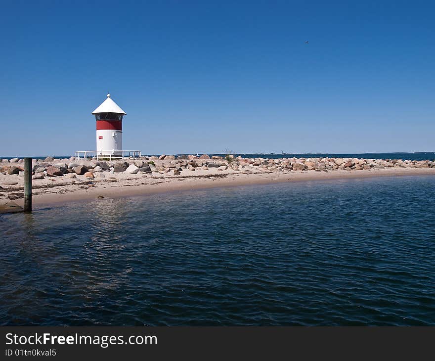 Small red and white lighthouse by the sea