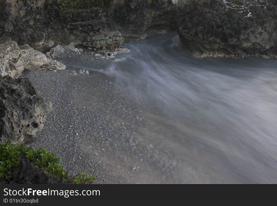 Swirling wave trails on coral over small beach. Swirling wave trails on coral over small beach