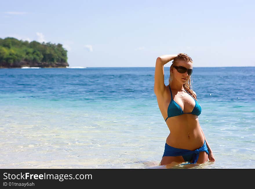 Blonde girl relaxing in water on the beach on Bali island in Indonesia