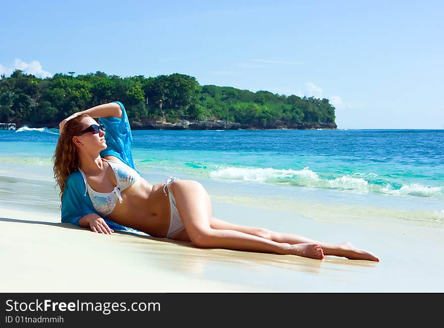 Beautiful brunette young girl relaxing on the sand beach on Bali island in Indonesia. Beautiful brunette young girl relaxing on the sand beach on Bali island in Indonesia