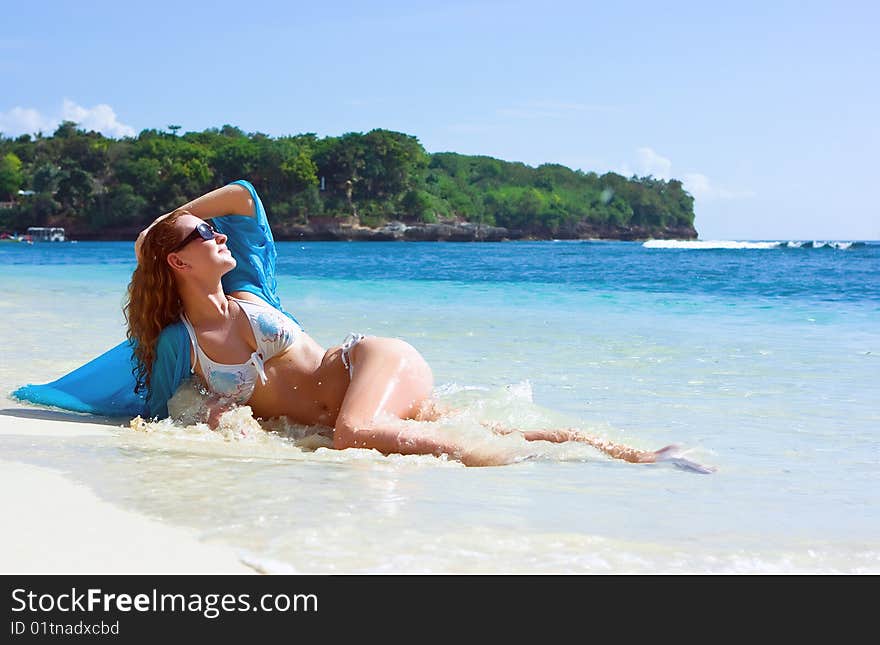 Beautiful brunette young girl relaxing on the sand beach on Bali island in Indonesia. Beautiful brunette young girl relaxing on the sand beach on Bali island in Indonesia