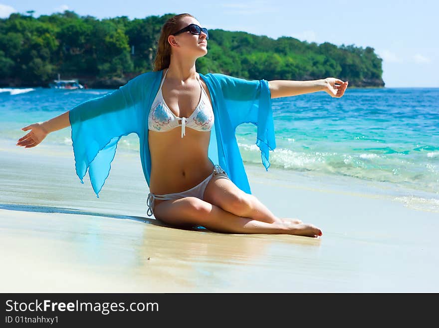 Beautiful brunette young girl relaxing on the sand beach on Bali island in Indonesia. Beautiful brunette young girl relaxing on the sand beach on Bali island in Indonesia