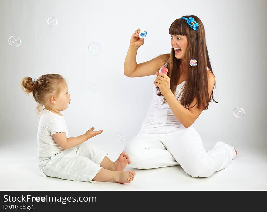 Little girl and her mother blowing bubbles