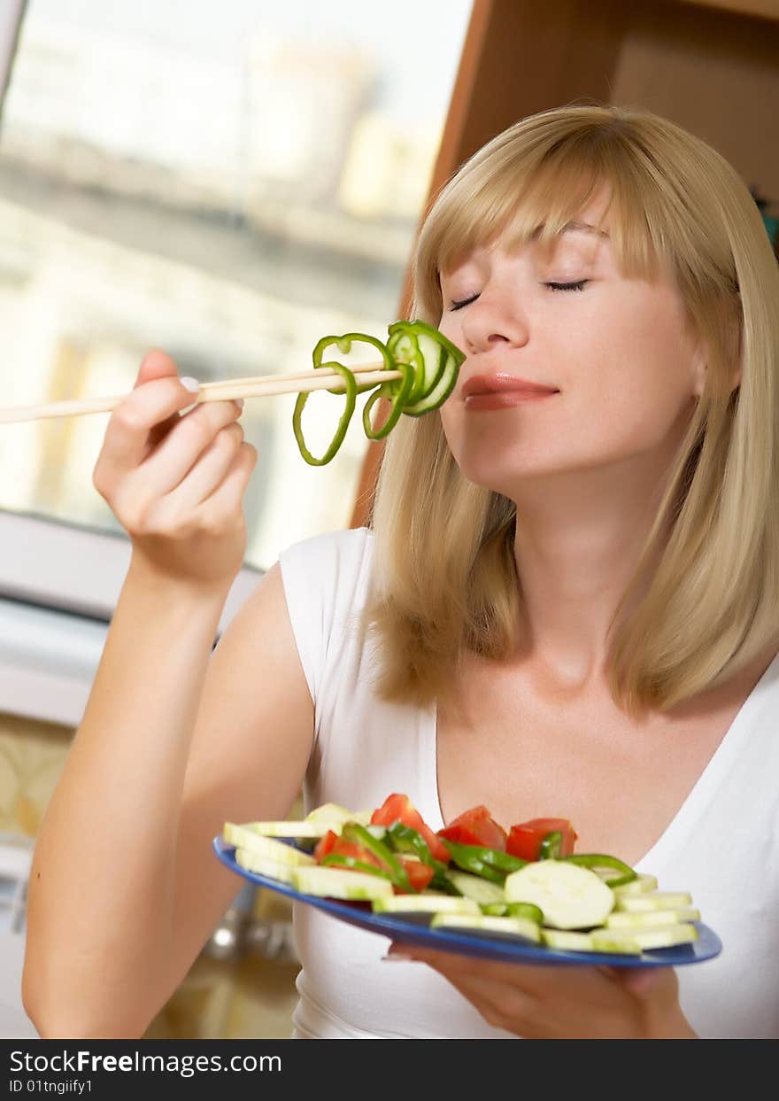 The young woman eats green salad. The young woman eats green salad