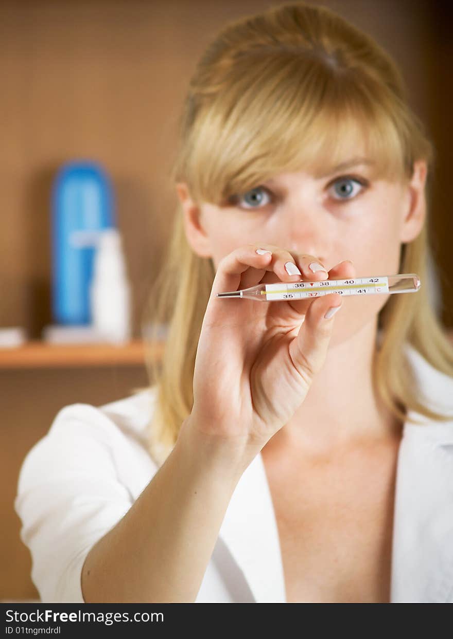 Closeup portrait of beautiful young female doctor looks at a thermometer. Closeup portrait of beautiful young female doctor looks at a thermometer