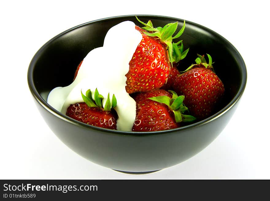 Whole red ripe strawberries with cream in a black bowl on a white background. Whole red ripe strawberries with cream in a black bowl on a white background