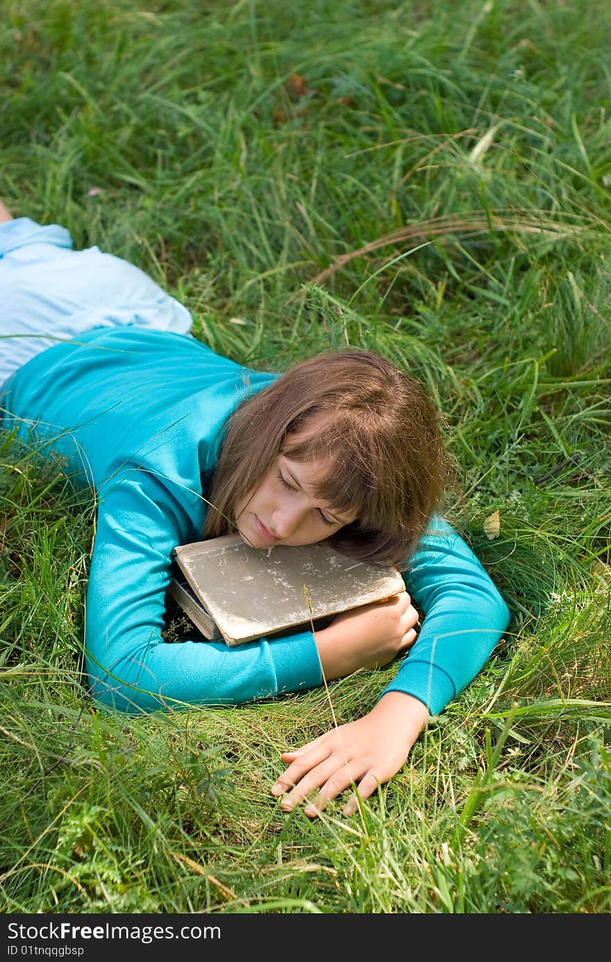 Young girl sleeping on a meadow with a book. Young girl sleeping on a meadow with a book