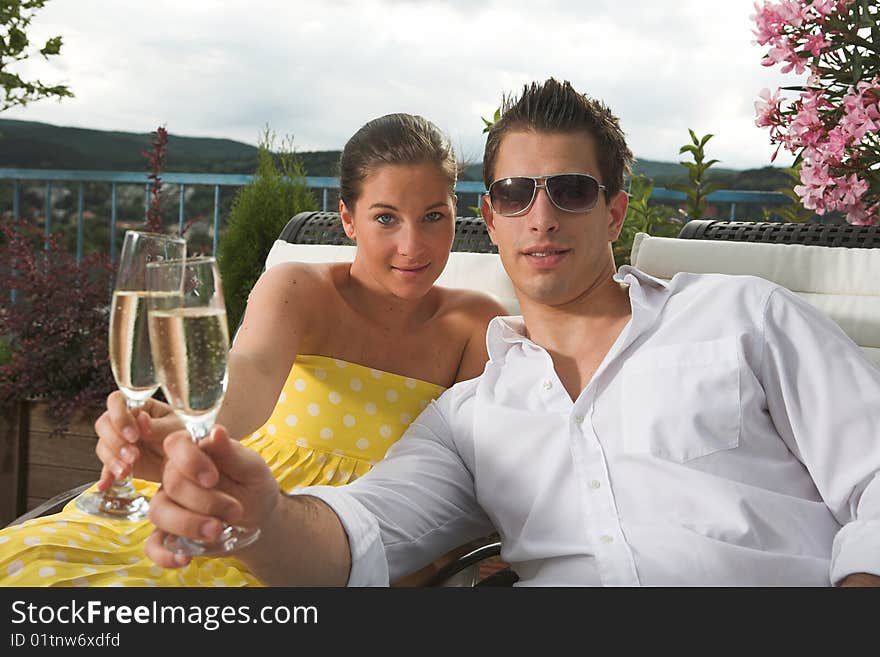 Stylish couple celebrating by having a drink on terrace. Stylish couple celebrating by having a drink on terrace