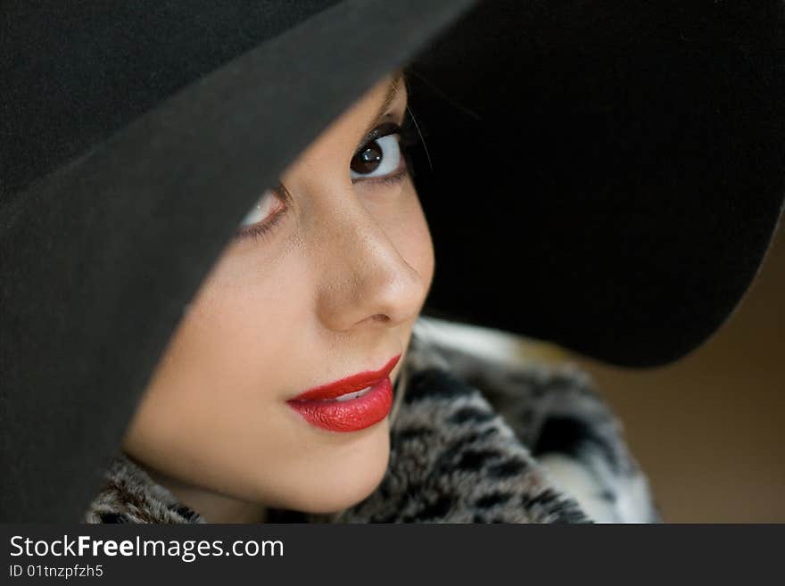 Lady shoots a glance under the hat. Lady shoots a glance under the hat