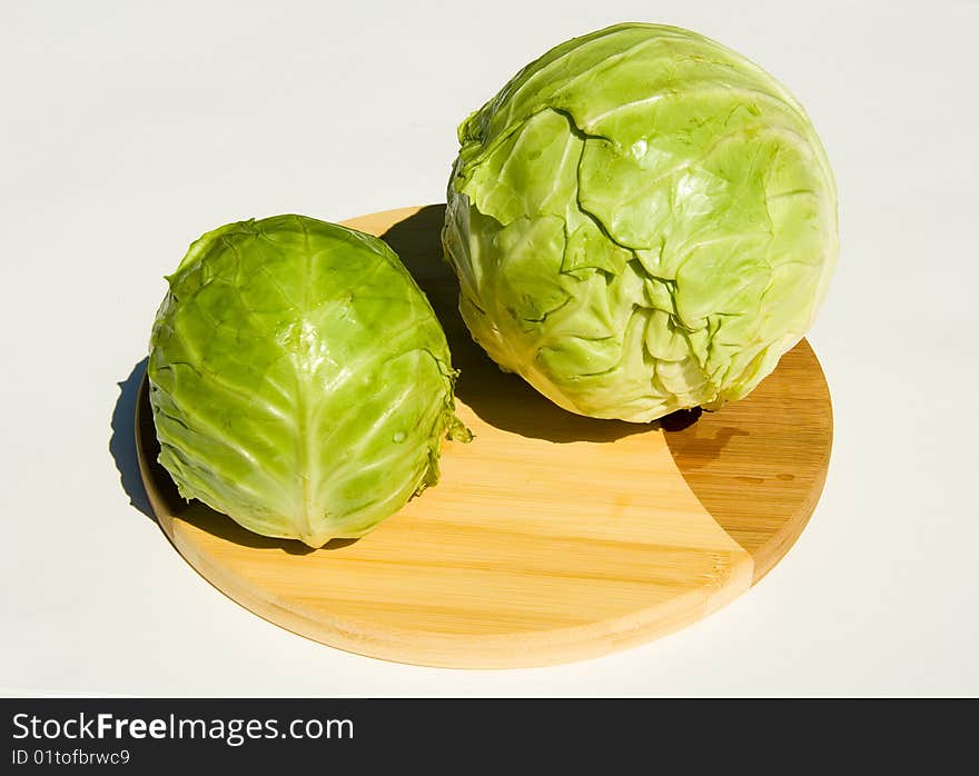 Two heads of cabbage on cutting board