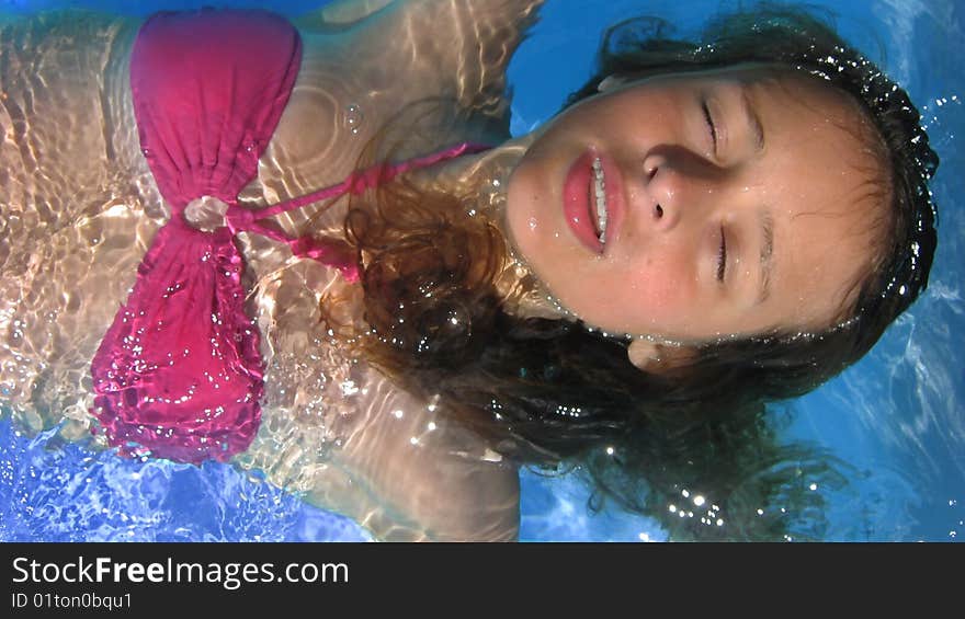 A young woman swimming on her back, drifting in a swimming pool. A young woman swimming on her back, drifting in a swimming pool.