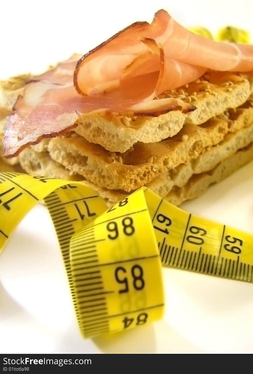 Whole wheat sesame crackers with smoked ham and measure tape in front. Whole wheat sesame crackers with smoked ham and measure tape in front