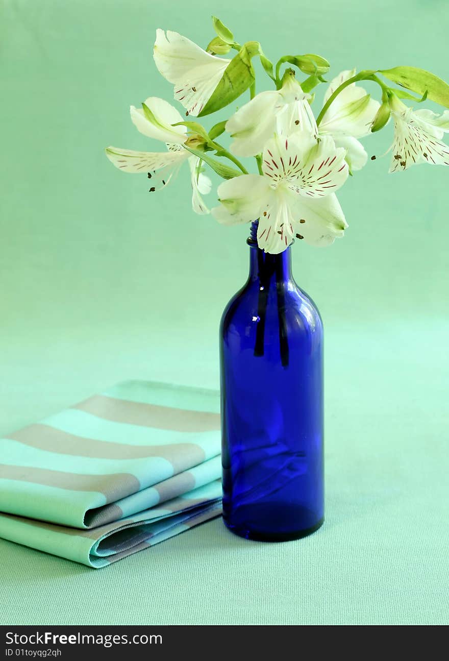 Blue Bottle With Flowers And Napkin.