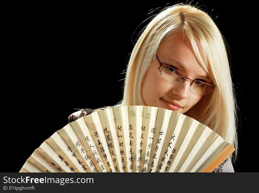 A young attractive woman with fan, isolated on black background