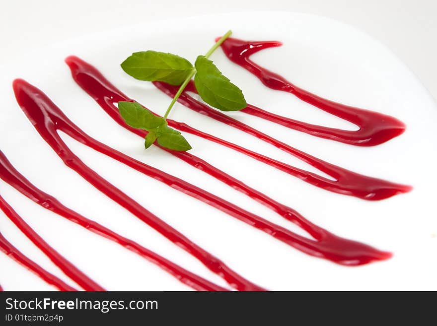 Elegant white plate decorated with cherry sauce and mint