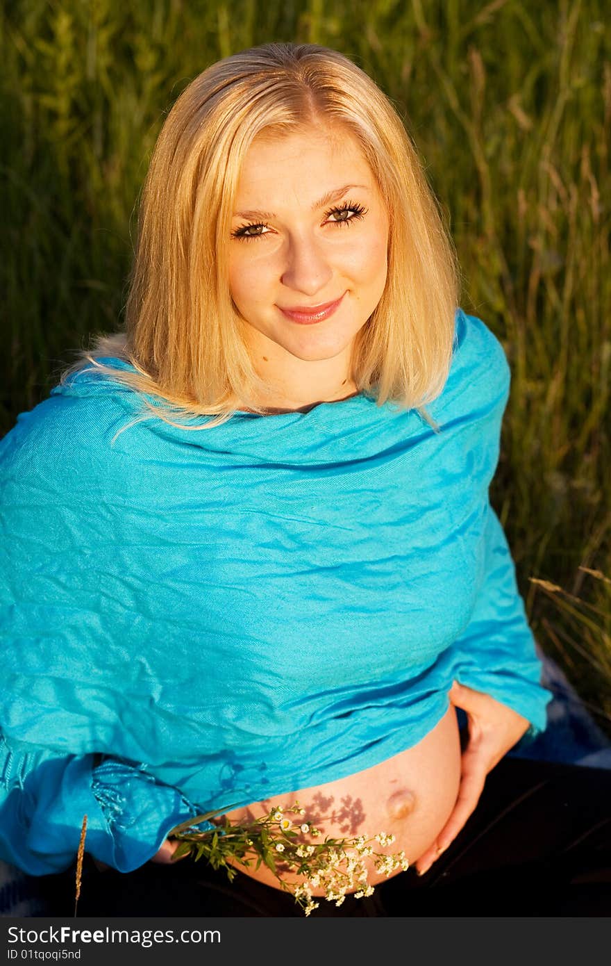 Pregnant Lady Sitting On The Grass With Flowers