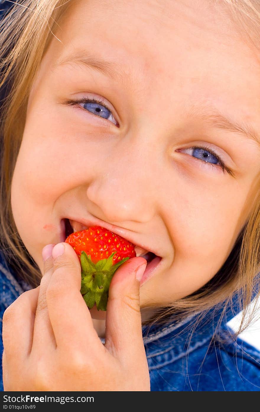 Girl in jeans dress eating strawberries. Girl in jeans dress eating strawberries