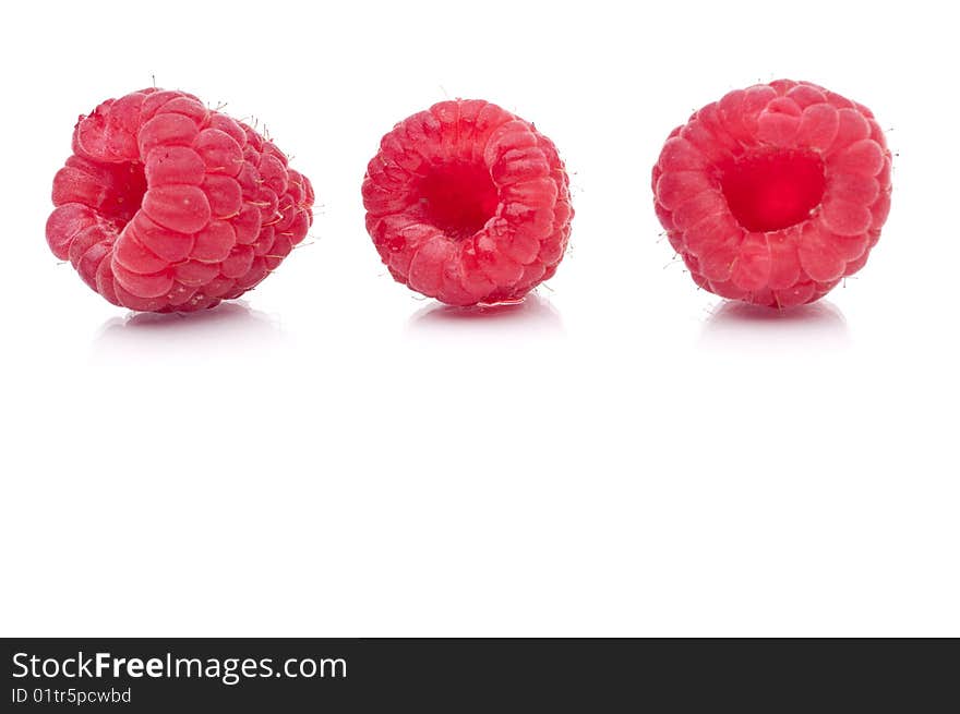 A horizontal image of three fresh raspberries on white