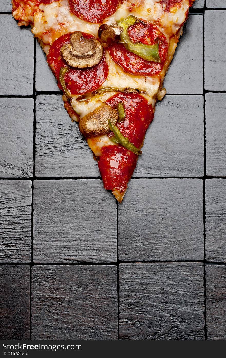 A slice of pizza on a black wooden background