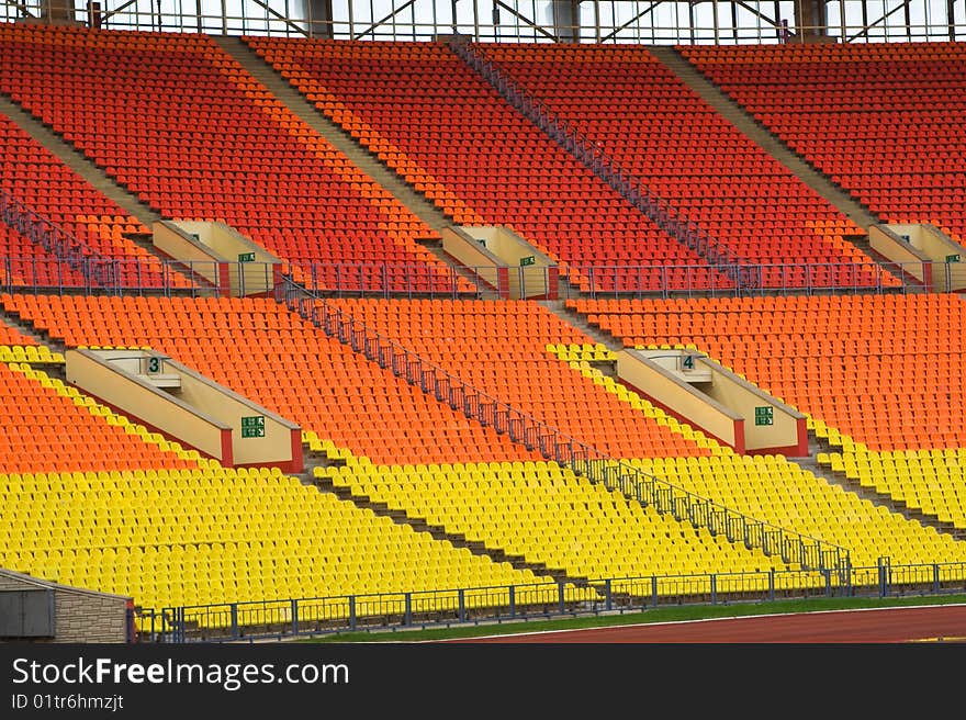 Rows of yellow, red and orange seats on the stadium with fences around the edges of the sectors