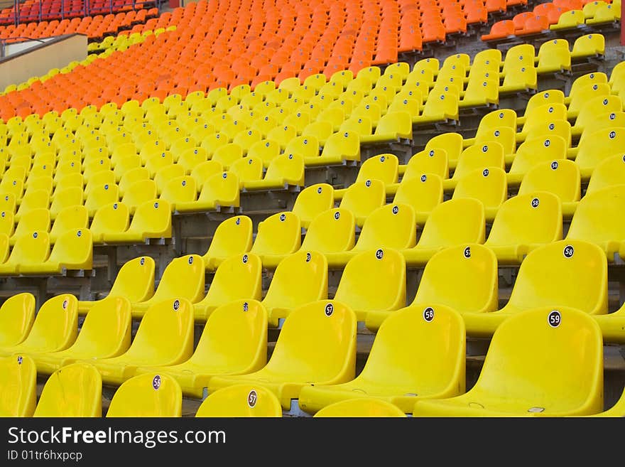 Rows of yellow, red and orange seats on the stadium with fences around the edges of the sectors